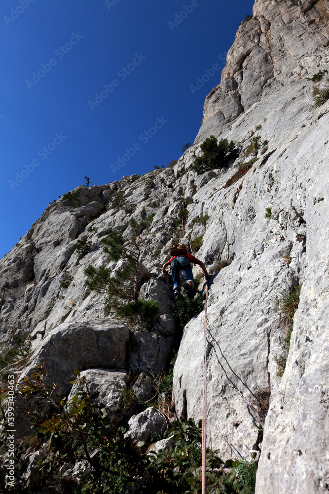 Young alpinist climbing the rocky route