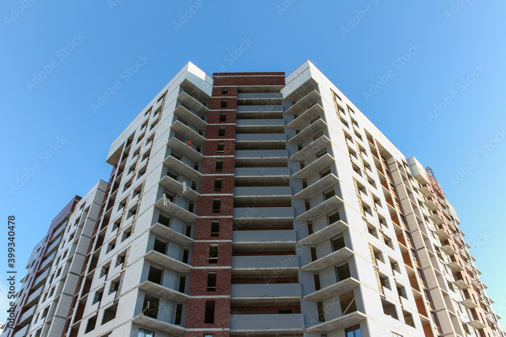 Contemporary urban architecture. Facade of a multi-storey building under construction. Brick building under construction. Contemporary urban architecture. Facade of a multi-storey building under construction. Brick building under construction.