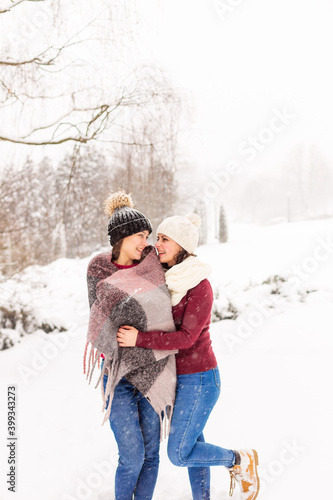 TWO GIRLS IN RED SWEATERS IN THE WINTER FOREST. THE SISTERS WALK IN THE SNOW IN THE PARK © Nadya Kolobova