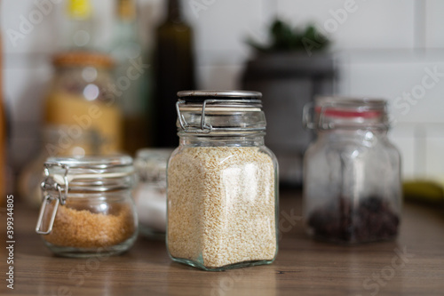 Side view of glass jar with sesame seeds, ingredients, kitchen equipment, vegetarian food, nutrition, preparing healthy meal, additives to the dish, recipe cooking, rustic style