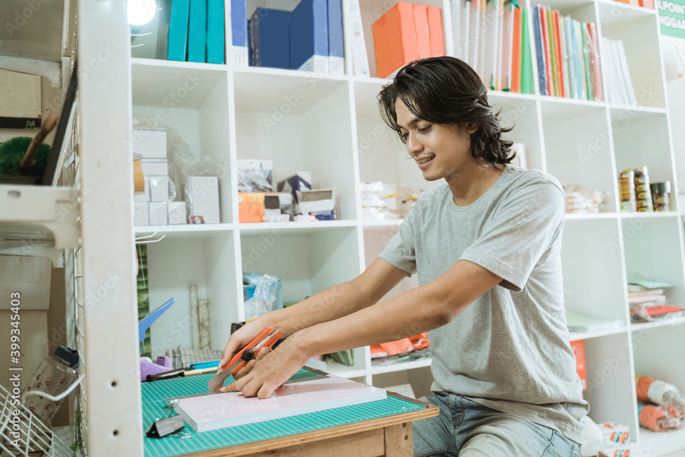 Young male entrepreneur working in a stationery shop. cutting up paper Young male entrepreneur working in a stationery shop. cutting up paper