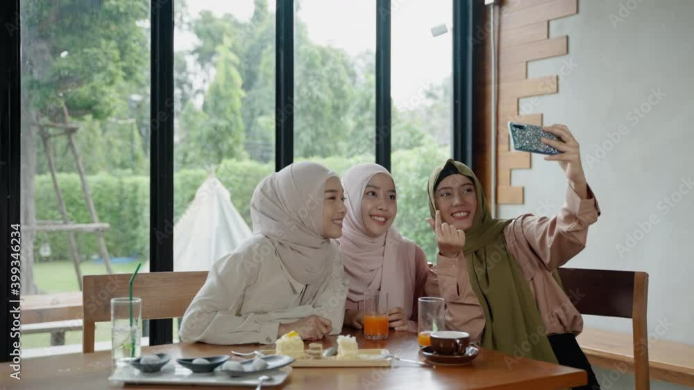 group of Muslim girls dining in a restaurant is using their mobile phones to selfies to show in social media.
