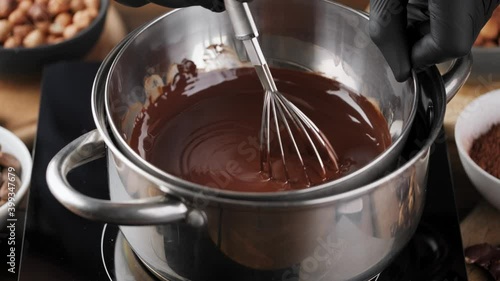 Hand stirring melted dark hot chocolate in a metal bowl. Process of cooking home made chocolate. Chocolate glaze.