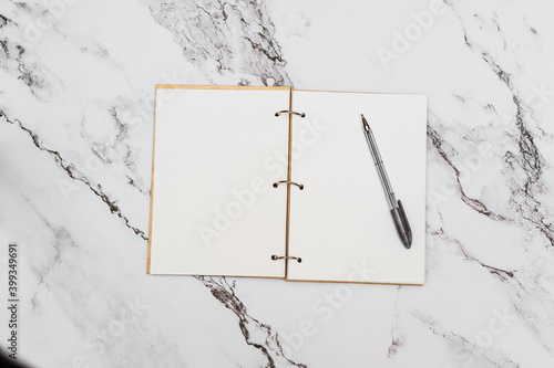 Wooden Notepad with white sheets with silver rings with black handle on marble background  surface
