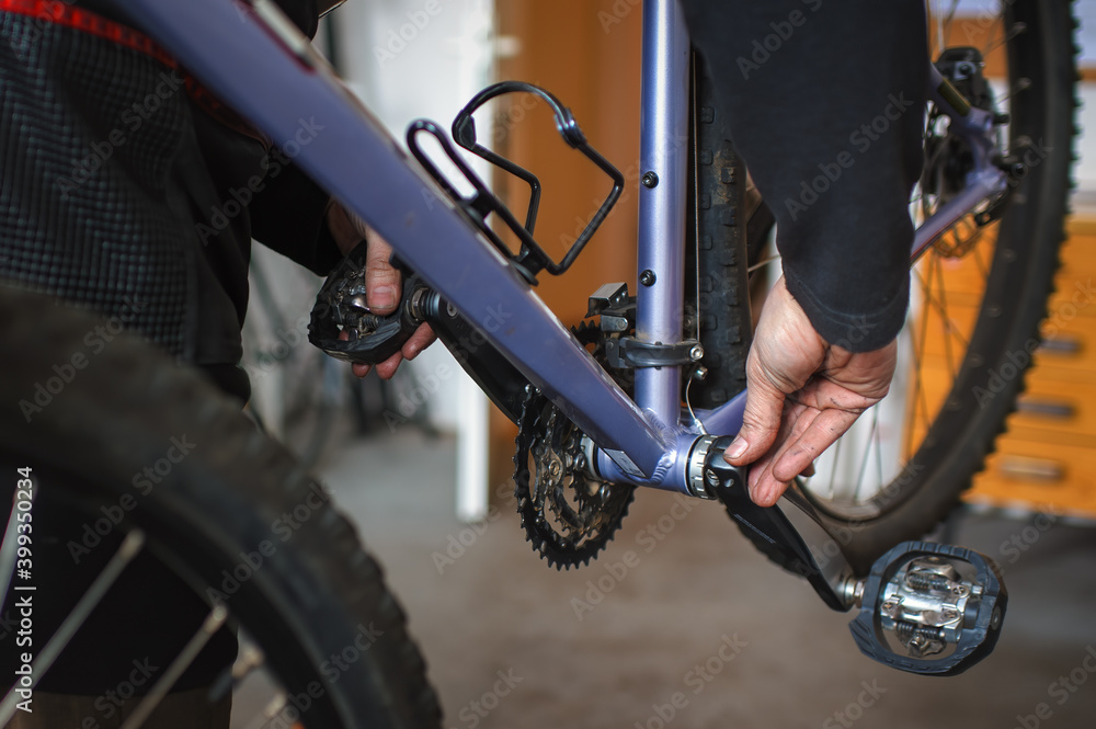 Hands of a mechanic holding a bicycle crank to check the clearance in the bottom bracket on a mountain bike. Hands of a mechanic holding a bicycle crank to check the clearance in the bottom bracket on a mountain bike.