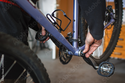 Hands of a mechanic holding a bicycle crank to check the clearance in the bottom bracket on a mountain bike. photo