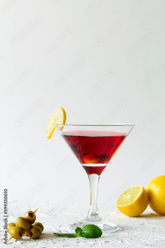 cosmopolitan cocktail. Martini glass with cocktail and olives on white background. Red cocktail with lemons and green mint on the table. copy space. alcohol drinks. vertical.