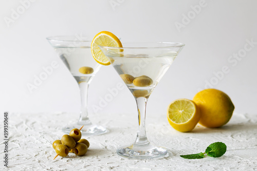 martini with lemon. Two Martini glasses with cocktail and olives on white background. Cocktail Margarita with lime and green mint on the table. copy space. alcohol drinks.