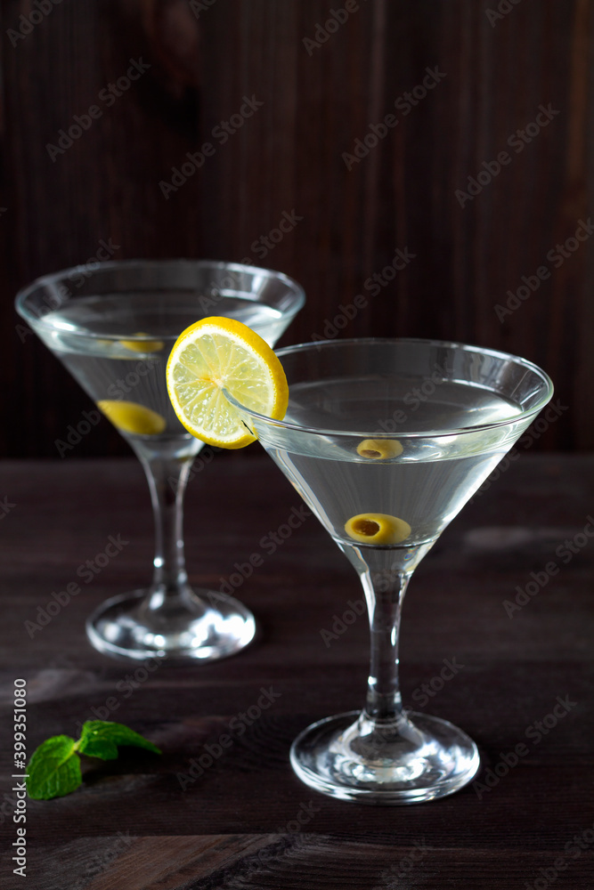 Two Martini glasses with cocktail and olives on black background. Cocktail Margarita with olive and green mint on the wooden table. copy space. alcohol drinks. vertical