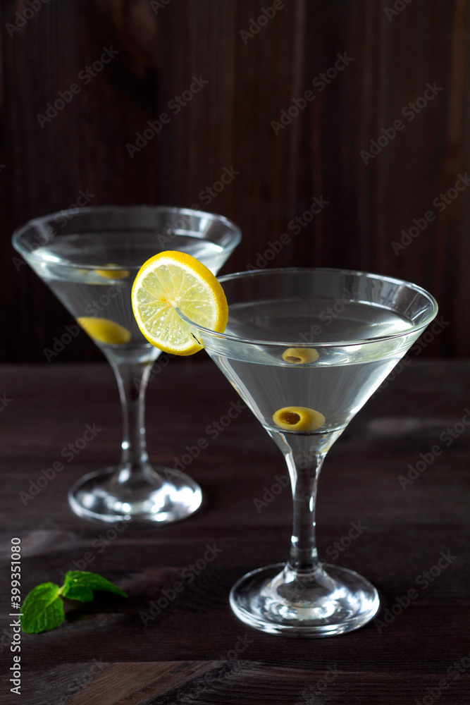 Two Martini glasses with cocktail and olives on black background. Cocktail Margarita with olive and green mint on the wooden table. copy space. alcohol drinks. vertical Two Martini glasses with cocktail and olives on black background. Cocktail Margarita with olive and green mint on the wooden table. copy space. alcohol drinks. vertical