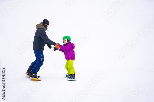 At Cold Winder Day at Mountain Ski Resort Father Teaching Little Daughter Snowboarding