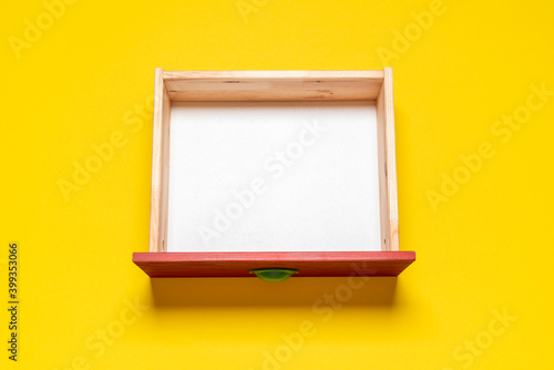 Billede på lærred Empty drawer top view. Wooden drawer on a yellow background.