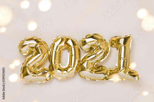 Gold and silver foil balloons numeral 2021, party decoration and confetti stars on beige background. Flat lay, christmas creative concept
