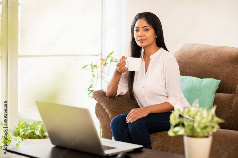 One woman, using laptop, domestic room, sitting on the cushion, holding coffee cup. One woman, using laptop, domestic room, sitting on the cushion, holding coffee cup.