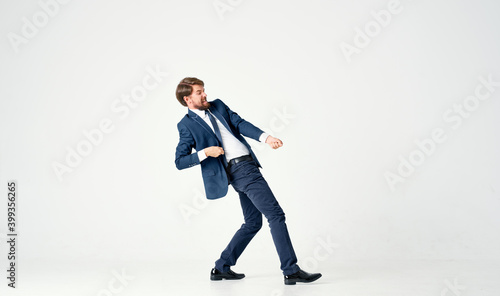a man in a suit pulls a rope on a light background in full growth