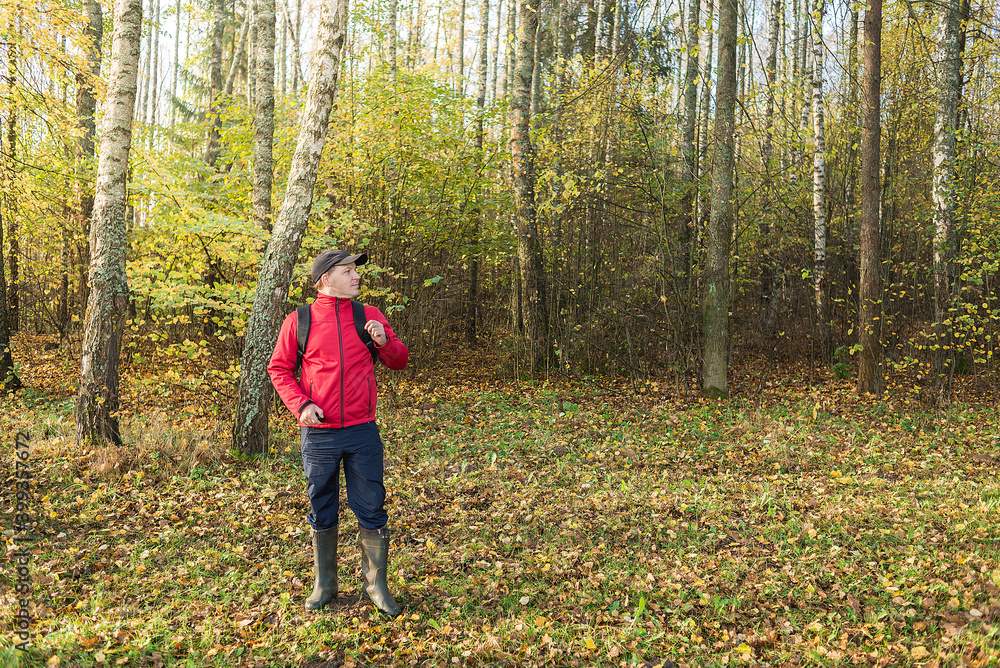 Young man with a backpack walks through the forest. Travel theme. Young man with a backpack walks through the forest Young man with a backpack walks through the forest. Travel theme. Young man with a backpack walks through the forest