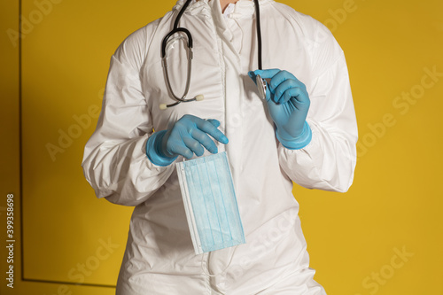 Doctor in white overall holding a mask and a stethoscope