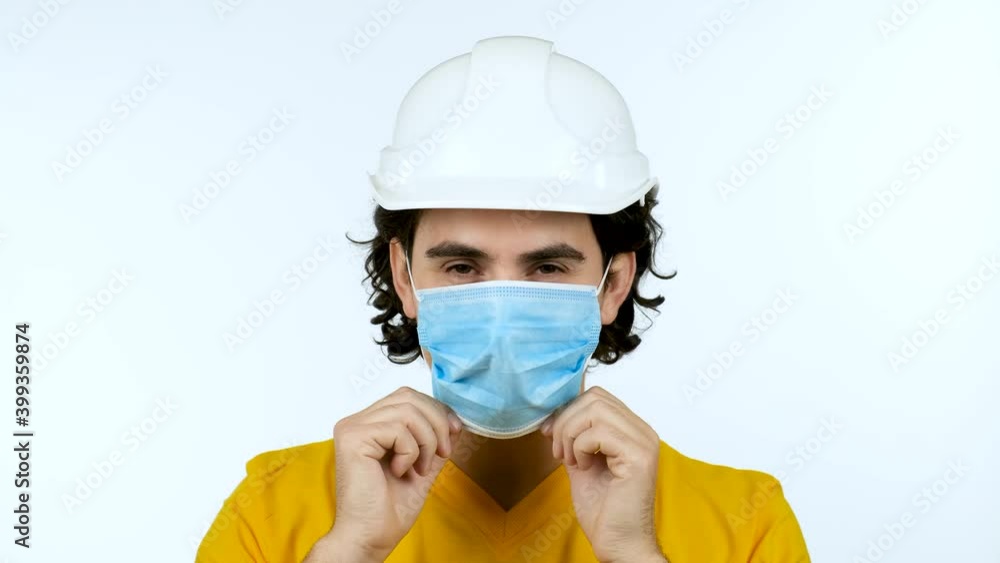 Student man worker showing thumb up gesture wearing protective helmet and face mask protection against the Covid-19 or coronavirus looking to camera isolated over white background. Student man worker showing thumb up gesture wearing protective helmet and face mask protection against the Covid-19 or coronavirus looking to camera isolated over white background.