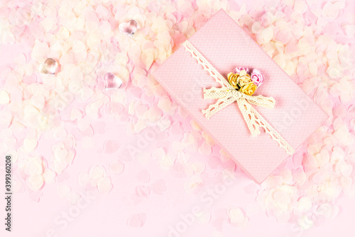 Pink gift box full of tender pink hearts of confetti on pastel background. Valentine's Day, wedding, love concept. Top view, flat lay, copy space.