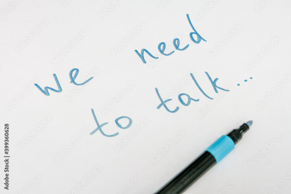 We need to talk message frase written on white piece of paper with a marker, communication problems in family or work office concept We need to talk message frase written on white piece of paper with a marker, communication problems in family or work office concept