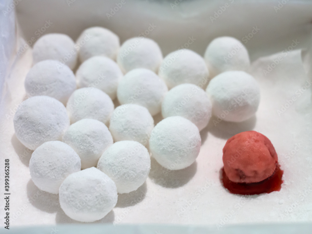 Cranberries in powdered sugar. One damaged red berry among whole white berries. A bunch of white berries stare at the crushed one. Cranberries in powdered sugar. One damaged red berry among whole white berries. A bunch of white berries stare at the crushed one.