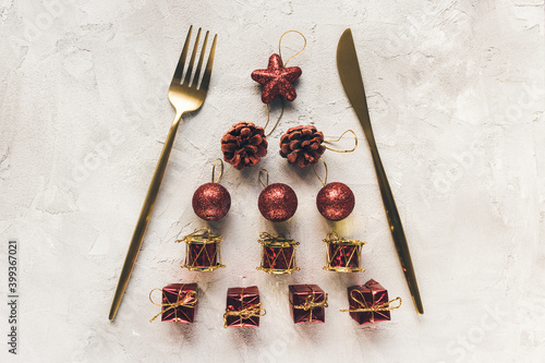 Fototapeta Naklejka Na Ścianę i Meble -  Elegant gold cutlery and red Christmas tree decoration on a gray background. Winter holidays cooking festive dinner, party menu and New Year celebration concept. Top view, flat lay, copy space