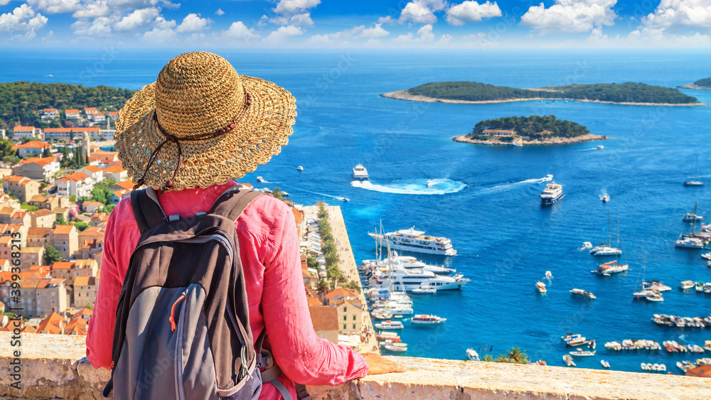 Coastal summer landscape with a tourist girl resting - top view of the City Harbour and marina of the town of Hvar from the fortress, on the island of Hvar, the Adriatic coast of Croatia