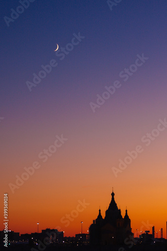 silhouette of the church on the background of sunset, in the sky a crescent
