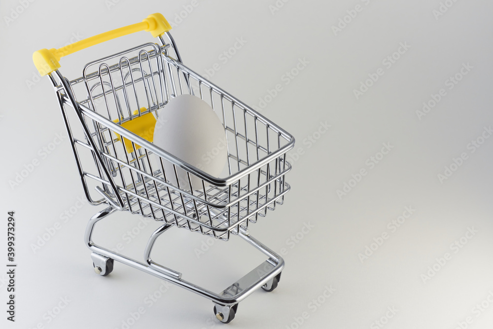 A shopping cart with an egg on a white background. A shopping cart with an egg on a white background.