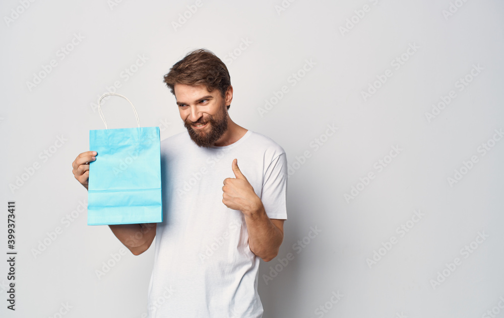 Bearded man in a white t-shirt with a package in his hand Shopping fun isolated background Bearded man in a white t-shirt with a package in his hand Shopping fun isolated background