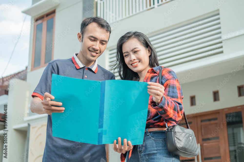 Asian male housing developer showing home certificates to beautiful women against a new home background Asian male housing developer showing home certificates to beautiful women against a new home background
