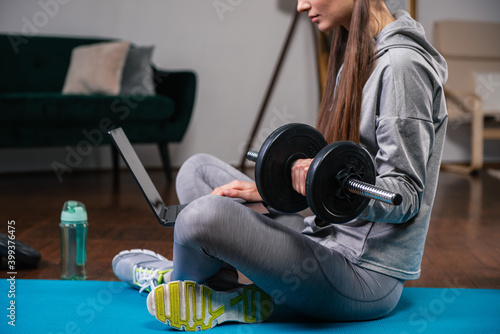 Young woman repeating exercises while watching online workout session. Quarantine training at home concept