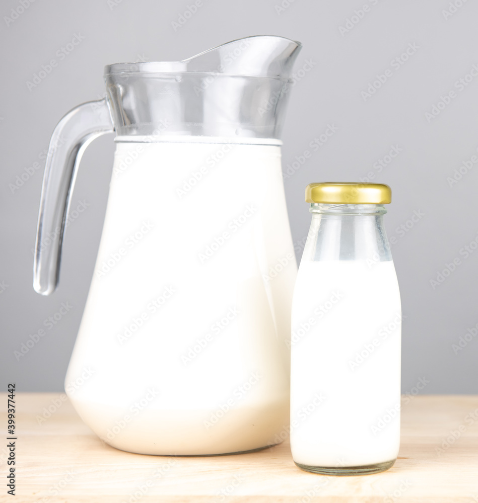 jug and bottle of fresh milk glass on wooden table background. .Raw milk is high in calcium and protein to drink for all ages..Milk consumption nutritious and healthy dairy products concept. jug and bottle of fresh milk glass on wooden table background. .Raw milk is high in calcium and protein to drink for all ages..Milk consumption nutritious and healthy dairy products concept.