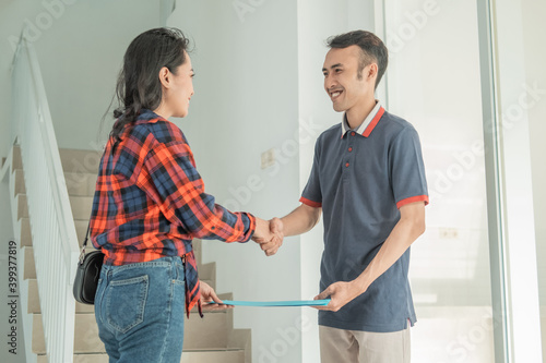 businessman housing developer handing home certificate to beautiful woman while shaking hands in the house