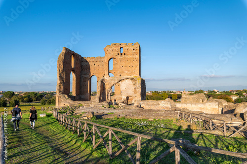 Villa dei Quintili, Rome, remains of the thermal baths, the caldarium Via Appia, on a day of blue sky a suggestive panoramic image of the brick building with tourists and the shadows of the fence.  photo