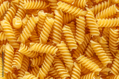 Dry pasta fusilli. Fusilli have spiral shape and yellow color. Pasta is delicious Italian traditional food made from wheat flour like noodles.Pasta background.Top view