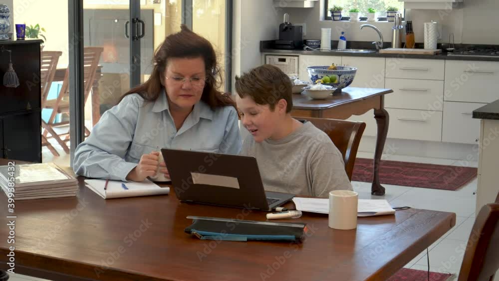 Slow motion view of a mature mother home schooling her son during Coronavirus Covid-19 lockdown Slow motion view of a mature mother home schooling her son during Coronavirus Covid-19 lockdown