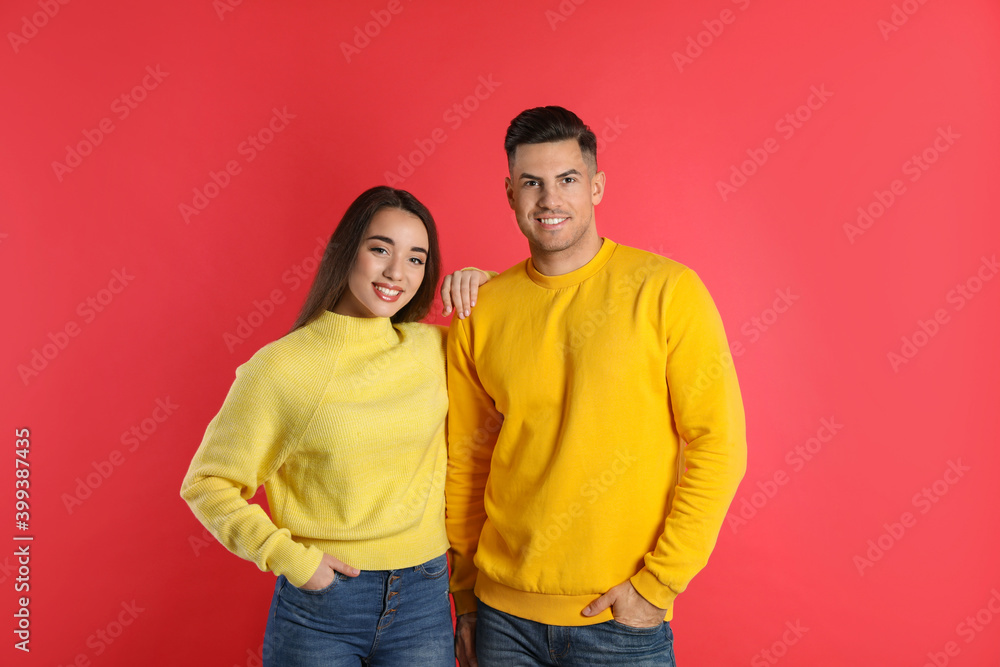 Happy couple wearing yellow warm sweaters on red background Happy couple wearing yellow warm sweaters on red background