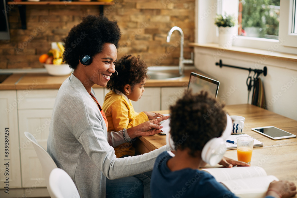 Happy black mother working while her children are learning at home. Happy black mother working while her children are learning at home.