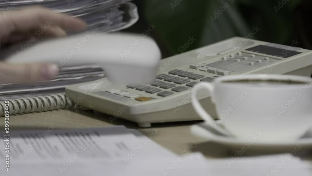 Office worker uses a phone to answer incoming calls and dialing a number to make a call. Businesswoman picking up the telephone. Close-up of women's hands, workplace Office worker uses a phone to answer incoming calls and dialing a number to make a call. Businesswoman picking up the telephone. Close-up of women's hands, workplace