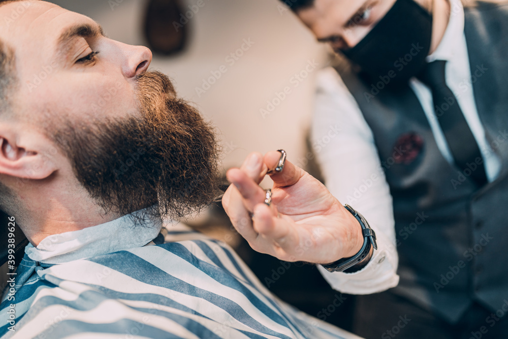Fototapeta premium Young good looking hipste man visiting barber shop. Trendy and stylish beard styling and cut.
