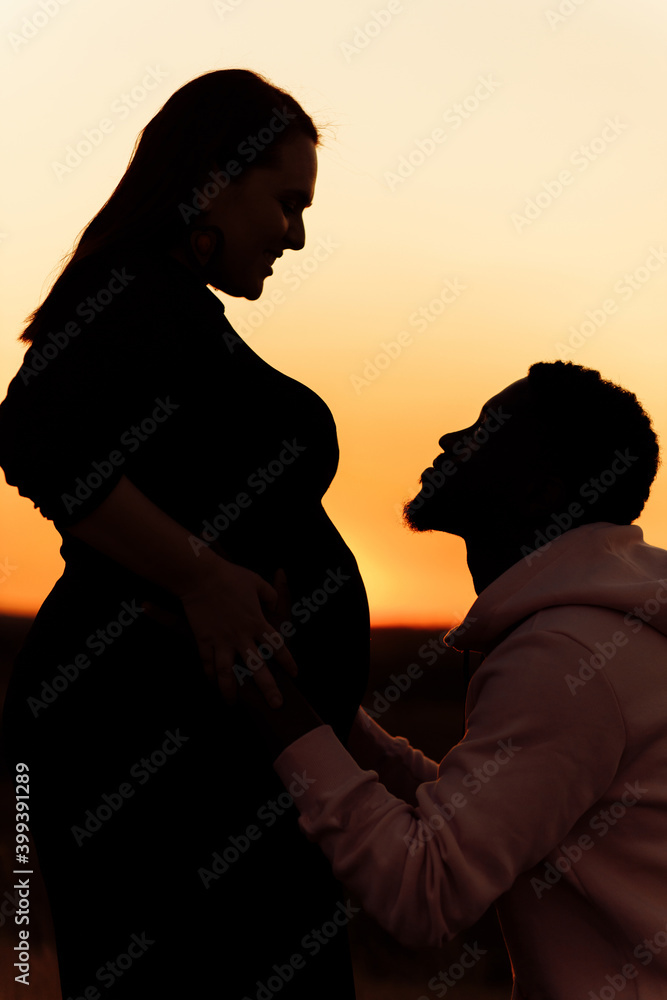 Silhouettes of lovely couple, overjoyed husband hug pregnant tummy of beautiful wife, young family expect for a baby, excited about parenthood, tender moments concept