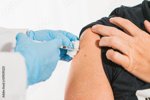 Covid vaccine. Doctor performs a vaccination on the patient's shoulder. Physician vaccinating a patient's shoulder. Influenza vaccination. Injection in the Arm. Injecting the coronavirus. Covid-19 © Tomaspf_