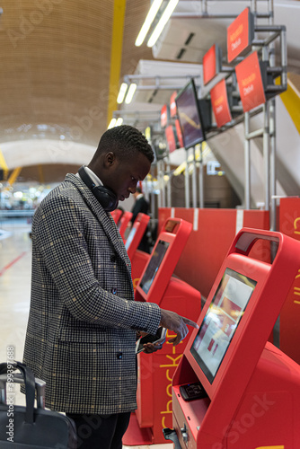 Young business man doing self check in a machine at the airport photo