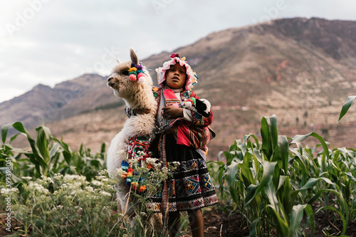 Peruvian indigenous girl looking at camera while holding an alpaca photo