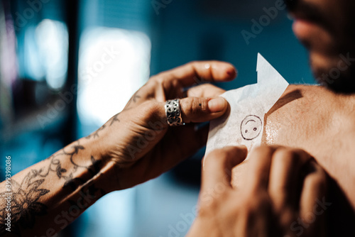 Crop tattooist transferring sketch on client shoulder photo