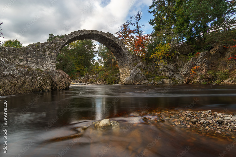 Fototapeta premium old stone bridge over red river in scotland at autumn
