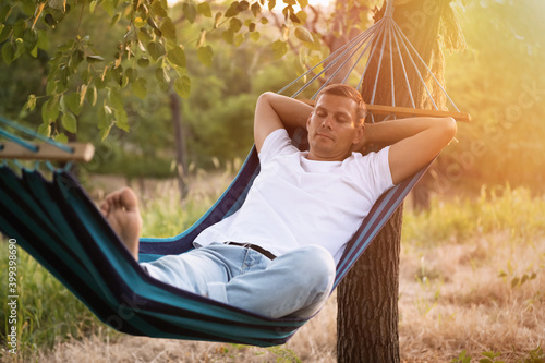 Man resting in comfortable hammock at green garden © New Africa