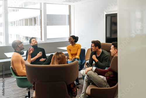 Contemporary group of coworkers in casual wear smiling while having conversation at office