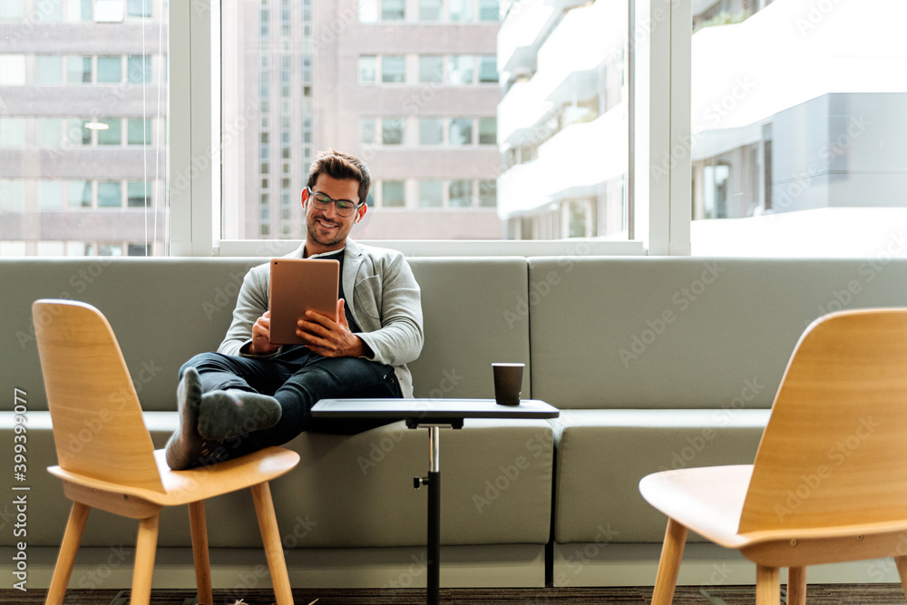© David Prado/Stocksy - Cheerful freelancer using tablet at workplace © David Prado/Stocksy - Cheerful freelancer using tablet at workplace